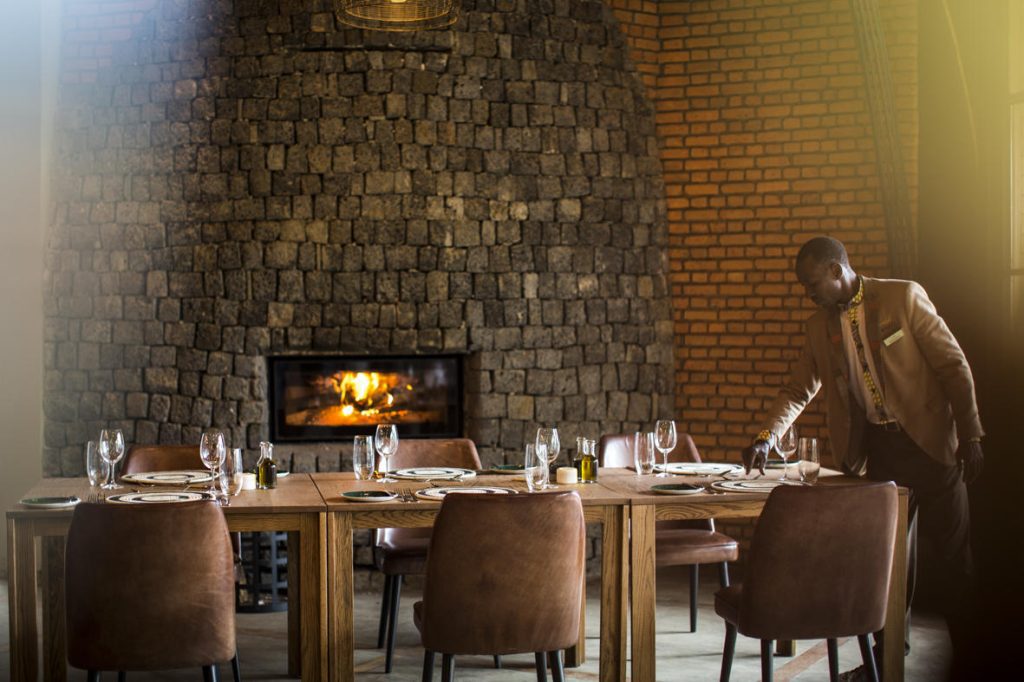 A dining table and fireplace at Wilderness Bisate lodge